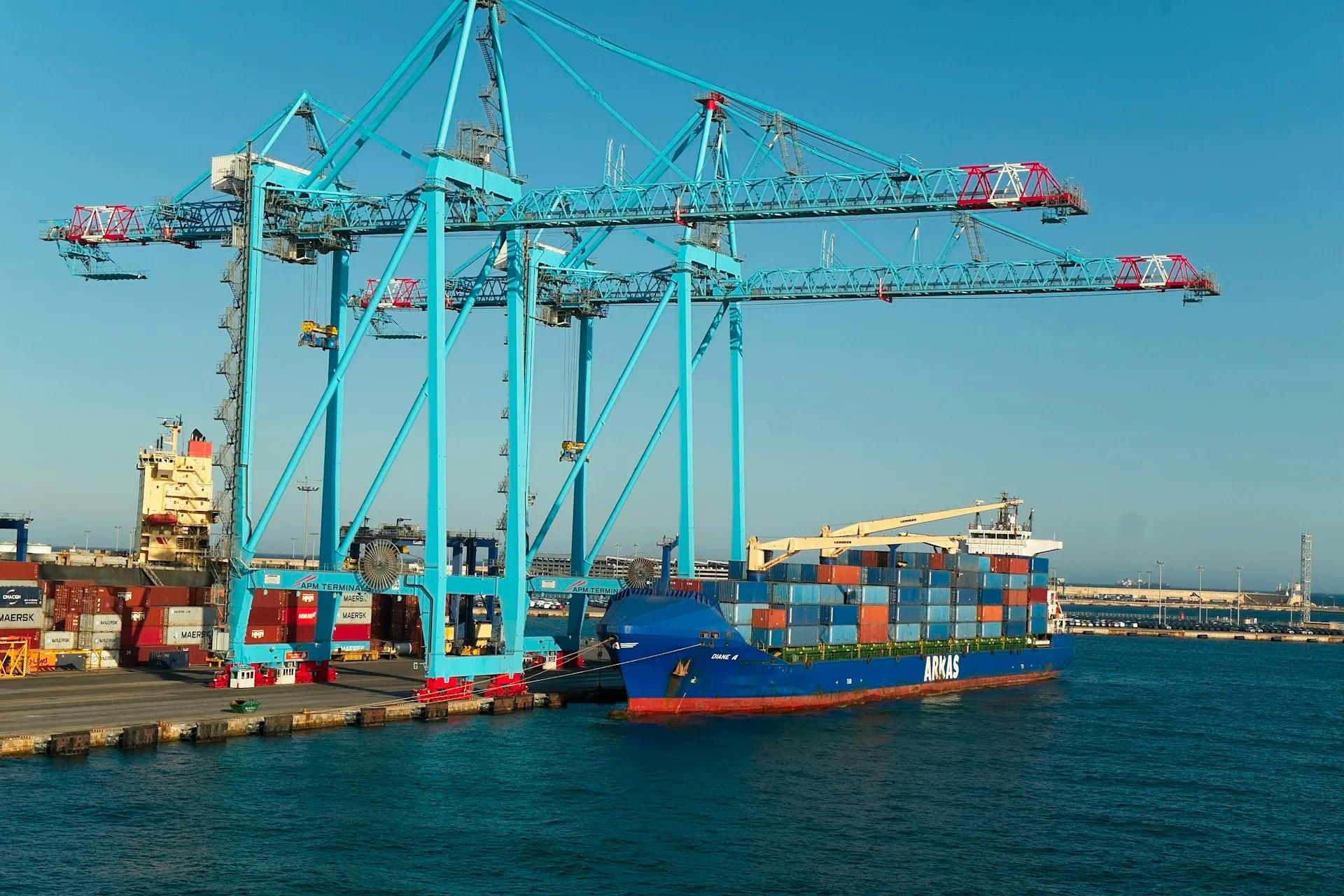 A container ship berthed at a terminal with gantry cranes